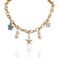 Collier à charms doré Elyora avec perles blanches, fleur turquoise, étoile de mer et papillon, assemblé à la main – bijou estival bohème chic pour femme.
